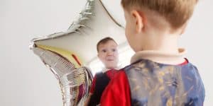 "ילד מחזיק בלון כסף בצורת כוכב ומשתקף בו, במסגרת פעילות טיפולית לחיזוק דימוי עצמי וביטוי רגשי."